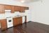 Modern kitchen with sleek hardwood floors, elegant cabinetry, and essential appliances offering a spacious cooking area.