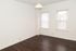 Bright and inviting room with elegant dark wood flooring and natural light streaming through two windows, perfect for a cozy home setting.