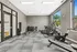 Modern fitness room with ample natural light, featuring state-of-the-art treadmills, exercise bike, and well-organized free weights area.