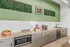 Contemporary kitchen space with sleek granite countertops, built-in coffee bar, and vibrant green accent wall, perfect for entertaining.