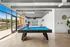 Bright and modern recreation room with a sleek billiards table, large windows, and stylish decor, perfect for relaxing and entertaining.