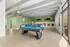 Modern and inviting recreation room featuring a sleek pool table, stylish seating area, and a contemporary kitchenette with bar seating, ideal for social gatherings.