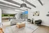 Chic open-concept living space with modern furniture, large windows, and a stylish kitchen with a pool table, perfect for entertaining.
