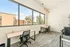 Bright modern workspace with large windows, featuring two desks and stylish decor, offering a vibrant view of the surrounding cityscape.
