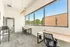 Bright office space with large windows offering scenic views, featuring modern desks and chairs for a comfortable work environment.
