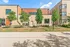 Modern apartment building exterior with sleek design and lush greenery under a bright blue sky.