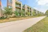 Contemporary apartment complex with spacious balconies and lush greenery, adjacent to a peaceful walking path.