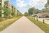 Inviting urban scene with modern apartment building, tree-lined pathway, and cozy neighborhood ambiance under a bright sky.