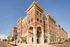 Charming red-brick apartment building with elegant archways and large windows, nestled in a vibrant urban setting.