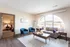 Bright and inviting living room with a large arched window, stylish modern furniture, and a seamless transition into a cozy bedroom.