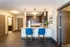 Modern apartment kitchen with elegant dark cabinetry, sleek appliances, and a stylish breakfast bar with blue chairs.