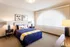 Bright and cozy bedroom with a plush navy bedspread, modern art pieces, and elegant lighting, exuding comfort and style.