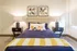 Inviting bedroom with modern decor, featuring a plush bed with stylish navy bedding, vibrant floral accents, and geometric artwork.