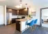 Modern kitchen with sleek dark cabinets, stainless steel appliances, and a stylish breakfast bar with blue chairs, ideal for entertaining.