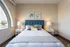 Elegant and cozy bedroom with a plush bed, stylish decor, and large arched window offering a scenic view.