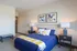 Inviting bedroom with modern decor featuring a cozy blue bed, abstract art, and soft lighting.