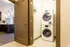 Modern apartment with in-unit laundry featuring stackable washer and dryer, adjacent to stylish kitchen.