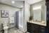 Elegant bathroom with modern fixtures, featuring a sleek vanity, chic dark cabinetry, and a luxurious bathtub with stylish shower curtain.