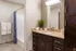 Elegant bathroom featuring sleek dark wood cabinetry, modern granite countertop, and cozy tub with stylish patterned shower curtain.