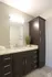 Sleek modern bathroom with elegant dark wood cabinetry, stylish granite countertop, and contemporary lighting.