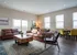 Inviting living room featuring plush leather sofas, large windows with natural light, and a stylish dining area with colorful chairs.