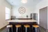 Modern kitchen with elegant island, sleek dark cabinets, stainless steel appliances, and chic decor featuring a large wall clock.