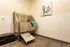 Modern pet grooming room with a sleek stainless steel wash station, bright art piece of a dog, and inviting tile flooring.