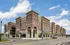 Elegant urban apartment complex featuring stylish brick architecture with modern retail spaces on the ground floor under a clear blue sky.