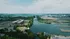 Aerial view of a picturesque riverside community with modern apartment buildings, lush greenery, and scenic waterway, offering serene and vibrant living environment.