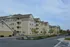 Modern apartment complex with multiple stories, featuring charming balconies and a well-maintained exterior set against a clear sky.