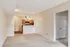 Bright open-plan apartment with a cozy living area leading to a modern kitchen with warm wood cabinetry and elegant pendant lighting.