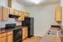 Contemporary kitchen with warm wooden cabinetry, sleek black appliances, and spacious countertops.