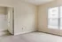 Inviting empty room with soft carpet, bright natural light from a large window, and an attached bathroom, perfect for customization and comfort.