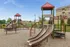 Charming playground with colorful slides and climbing structures in a peaceful residential community.