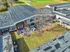 Aerial view of a modern apartment complex with a well-maintained courtyard, mature trees, and inviting outdoor seating, surrounded by lush greenery.