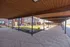 Inviting walkway with wooden roof and elegant landscaping leading to charming brick apartments, perfect for relaxed community living.