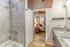 Modern apartment bathroom with elegant granite countertops, sleek tile shower, and a cozy bedroom view with warm lighting.