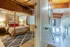 Inviting apartment interior featuring a cozy bedroom with a stylish bed frame, warm lighting, and plush rug, overlooking an elegant staircase with wooden accents.