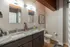 Modern bathroom with dual sinks, elegant lighting, and sleek granite countertops complementing the chic decor.