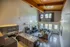 Contemporary living space showcasing a high ceiling with wooden beams, open-concept layout, stylish kitchen, and cozy sectional sofa by large windows.