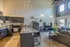 Modern open-concept kitchen and living room with high ceilings, stylish cabinetry, luxurious countertop, and cozy seating area bathed in natural light.