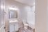 Inviting and modern bathroom showcasing elegant lighting, a sleek vanity, and a pristine shower-tub combo. Perfect for relaxation and rejuvenation.