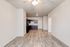 Modern open-concept apartment with sleek hardwood floors and a cozy kitchen featuring dark cabinetry.