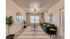 Modern living room with a cozy green sofa, stylish round mirror, elegant ceiling fan, and abundant natural light from large windows.