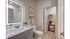 Elegant bathroom with modern illuminated mirror, sleek vanity, and cozy towel storage, offering a serene and stylish retreat.