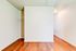 Bright room with elegant wood flooring, showcasing a spacious walk-in closet with clean white walls and a well-lit hallway.