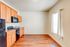 Bright kitchen with sleek wooden cabinets, modern appliances, and rich hardwood flooring, inviting natural light through a large window.