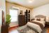 Elegant bedroom with cozy double bed, stylish wooden furniture, and warm lighting. Features a decorative rug and lush potted plant for a homely ambiance.