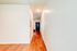 Bright and inviting hallway with sleek wooden flooring and a modern front door, perfect for welcoming guests.