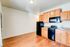 Contemporary kitchen with sleek black appliances, warm wood cabinetry, and elegant hardwood flooring.